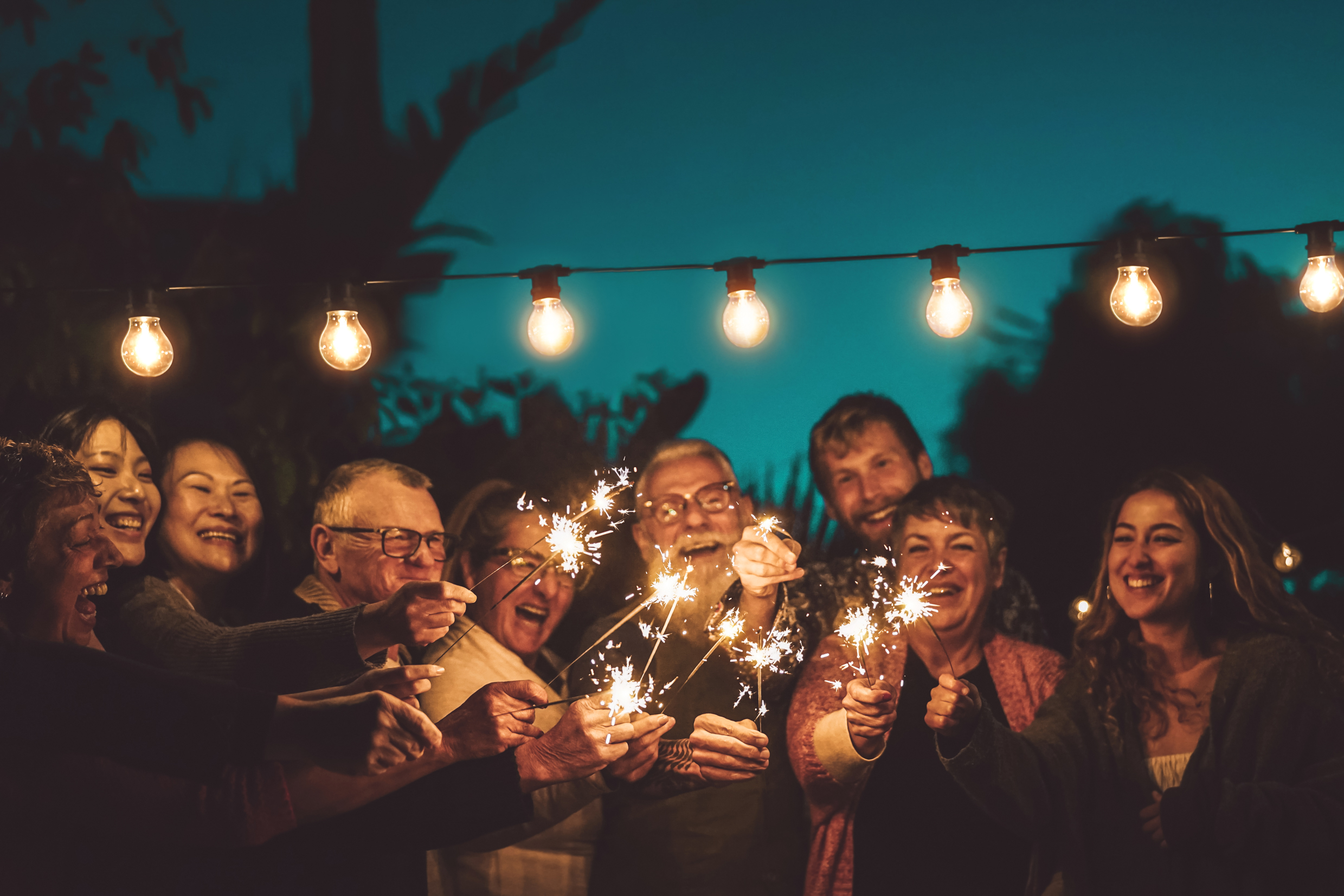 Happy Family Celebrating With Sparkler At Night Party Outdoor -