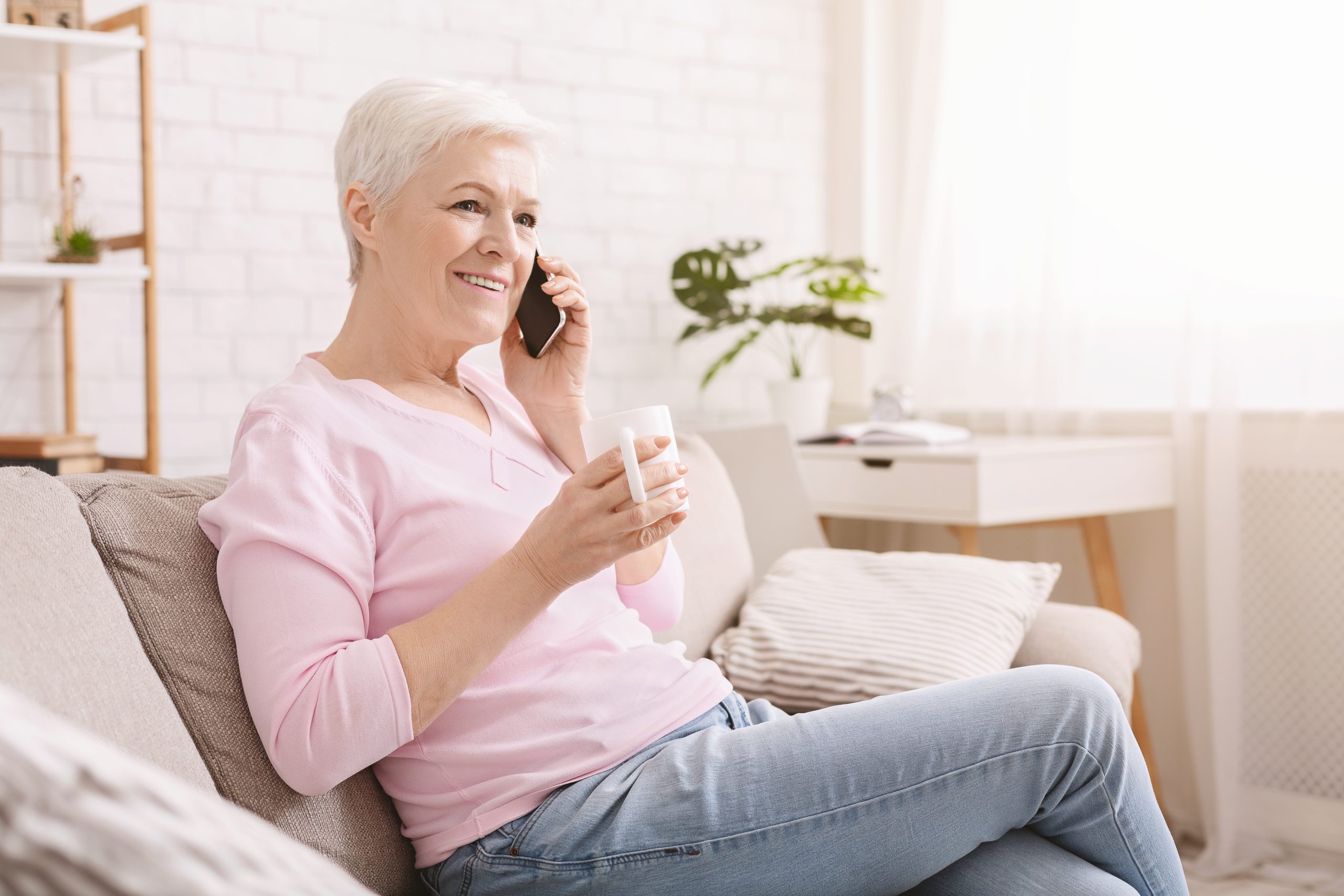 Cheerful senior lady having phone call on her smartphone